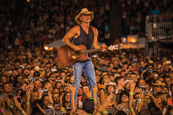 Kenny Chesney playing on stage in front of a huge crowd